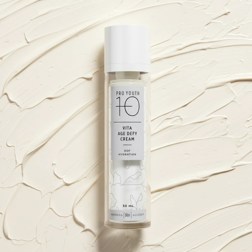 Pro Youth 10 Vita Age Defy Cream bottle on a cream smear background