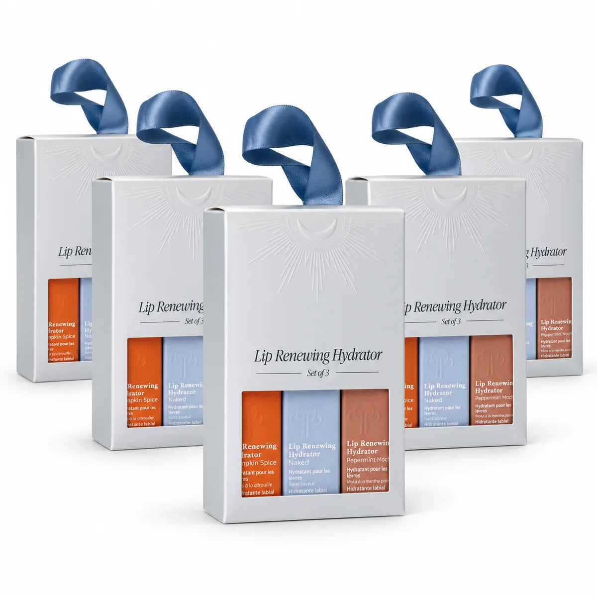 Six white cosmetic gift boxes arranged in a fan shape on a white background. Each box has a blue ribbon handle and a clear window showing three lip care strips in orange, blue, and brown packaging.