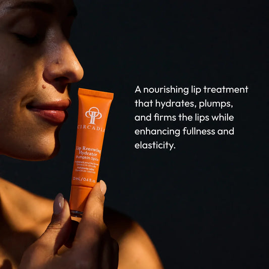 A woman holds an orange tube of Circadia Lip Remolding Hydration Lip Balm against a dark background, with white text describing the nourishing lip treatment.