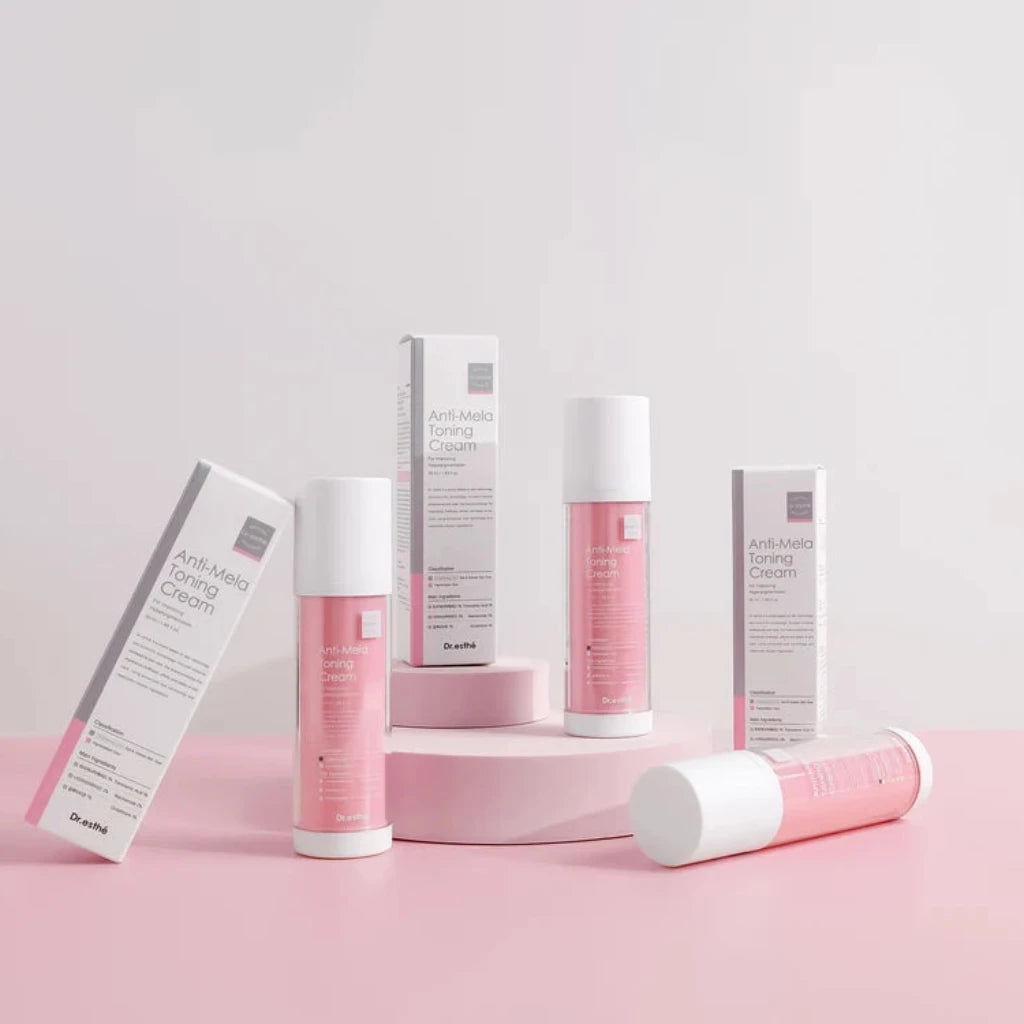 Dr. Esthe Anti Mela Toning Cream featuring pink and white bottles and boxes arranged on a pink surface against a light gray background.