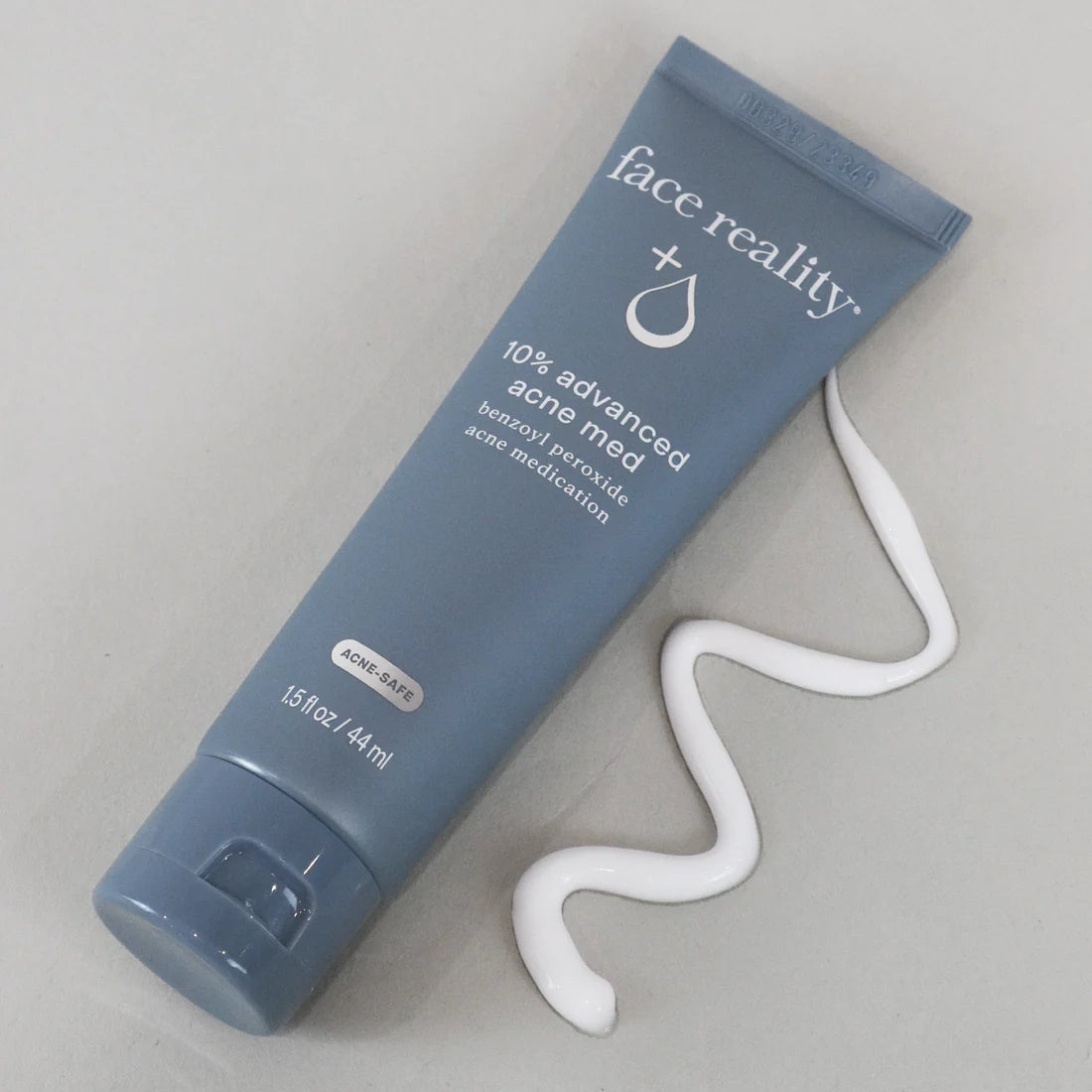 Blue tube of 'face reality' 10% advanced acne medication with white gel on a gray background