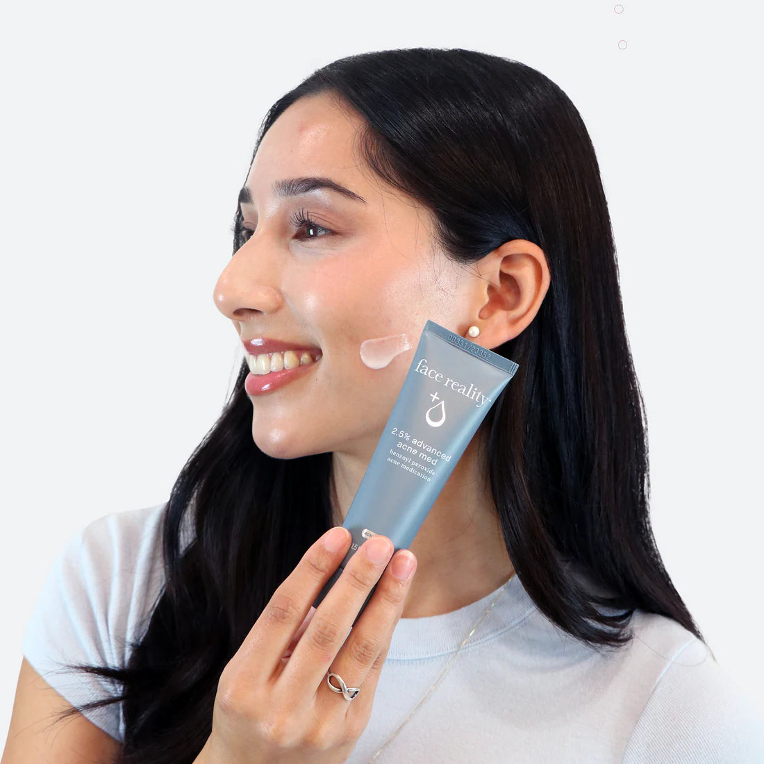 Woman applying skincare product to her face with a white background