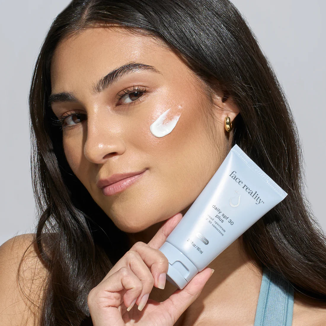 Face Reality Daily SPF 30 Plus sunscreen woman holding product