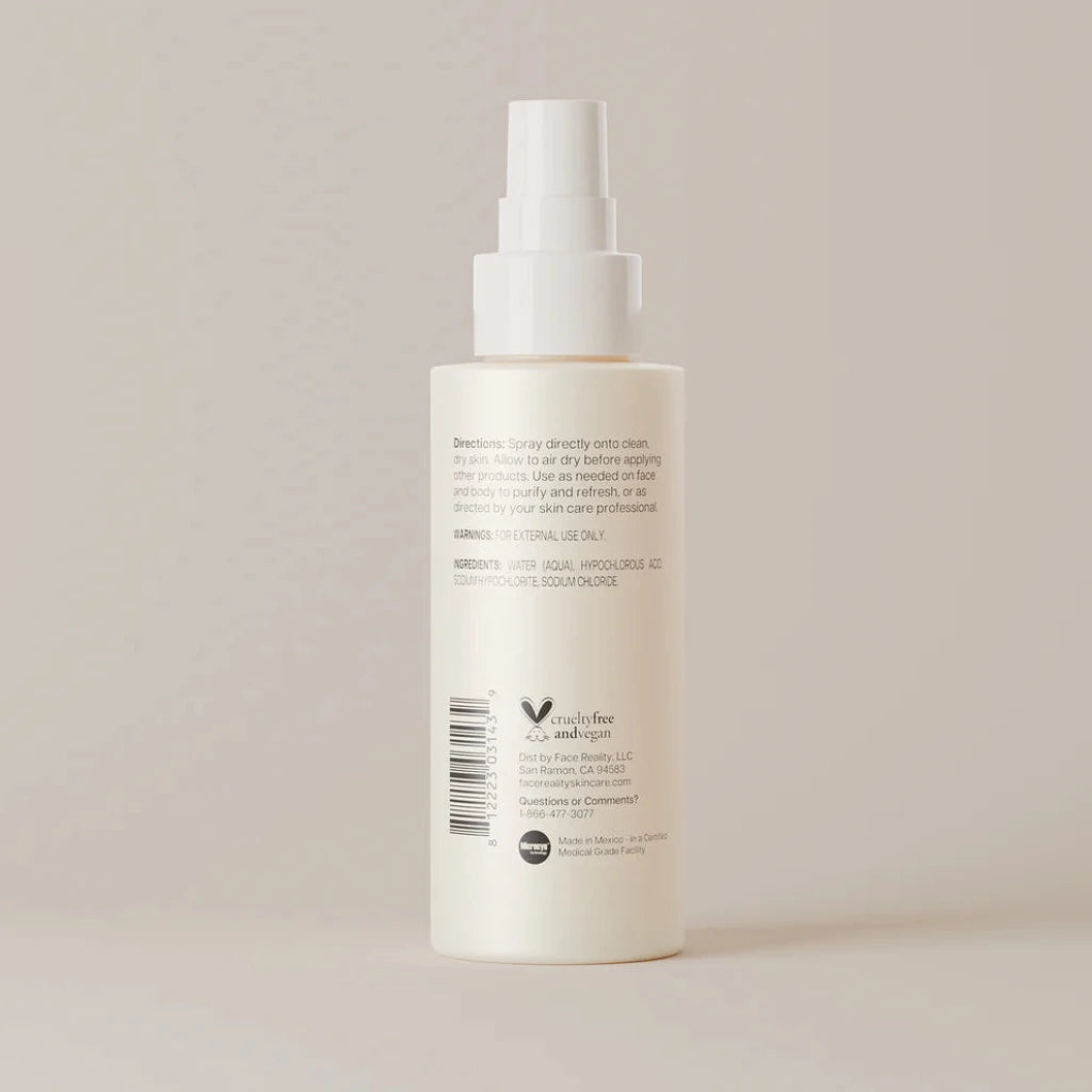 A tall, off-white pump bottle with a white spray nozzle, showing the back side with printed text and a barcode, set against a solid, warm beige background.