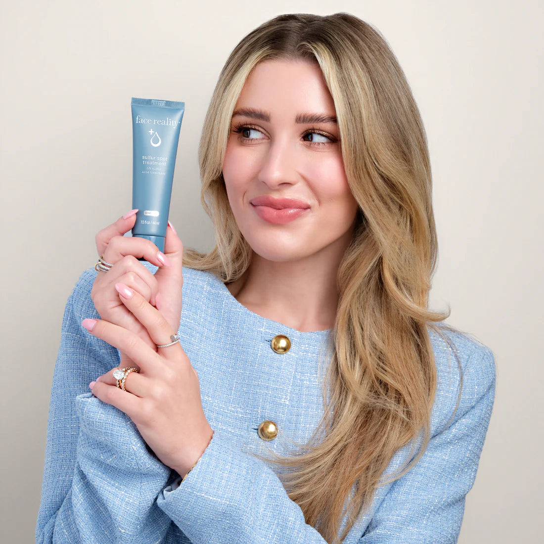 woman holding blue tube of Face Reality Sulfur Spot Treatment
