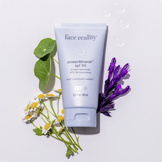 Tube of 'face reality' powerMineral SPF 50 sunscreen with flowers on a light background