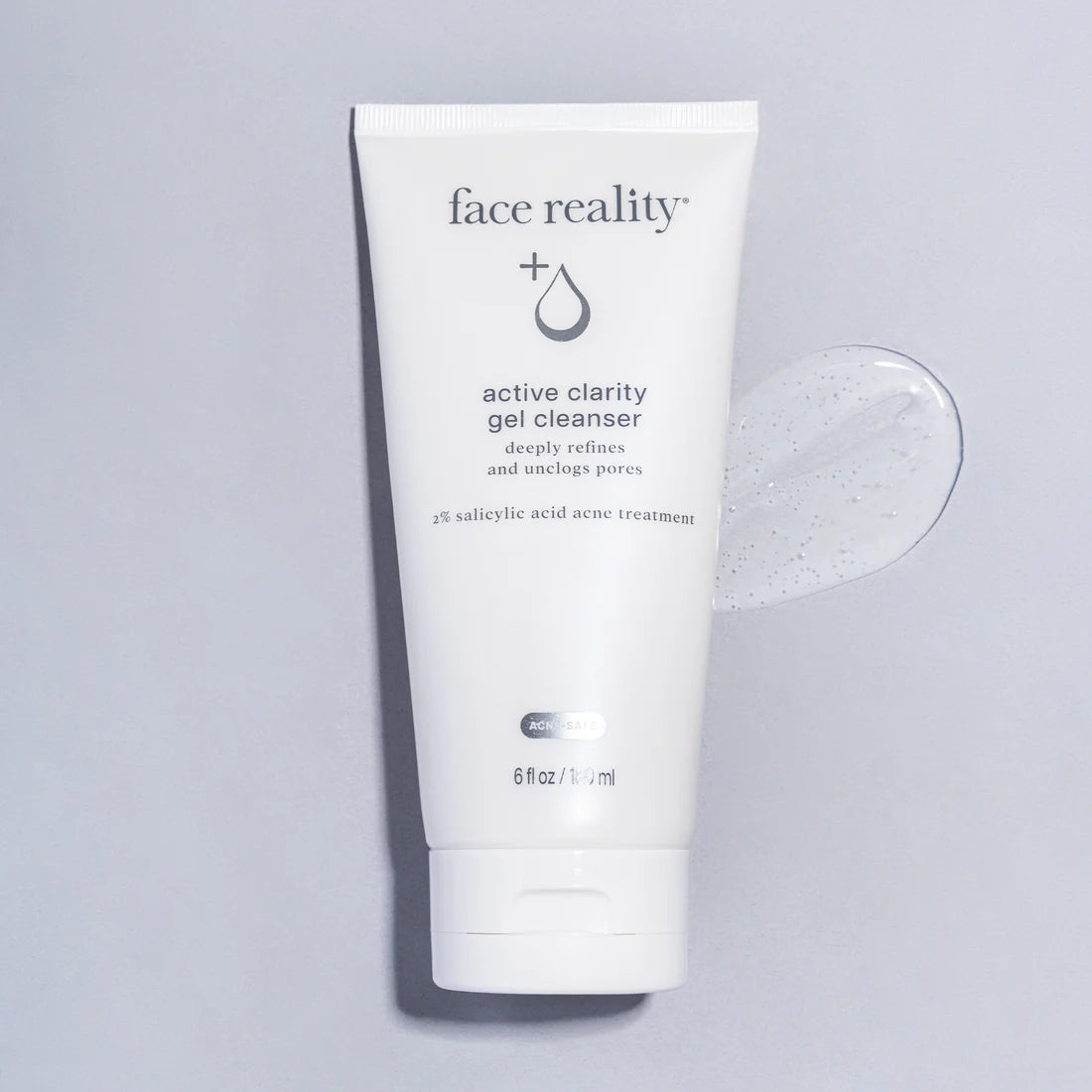 A white squeeze tube of face reality + Active Clarity Gel Cleanser standing upright on a light gray background, with a translucent gel product smear shown to the right.