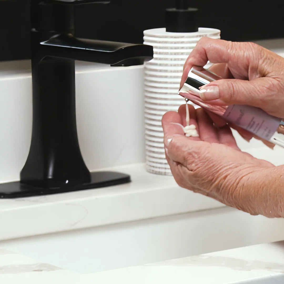 Person dispensing Glymed Plus Age Defying Masque in a bathroom setting with a black faucet
