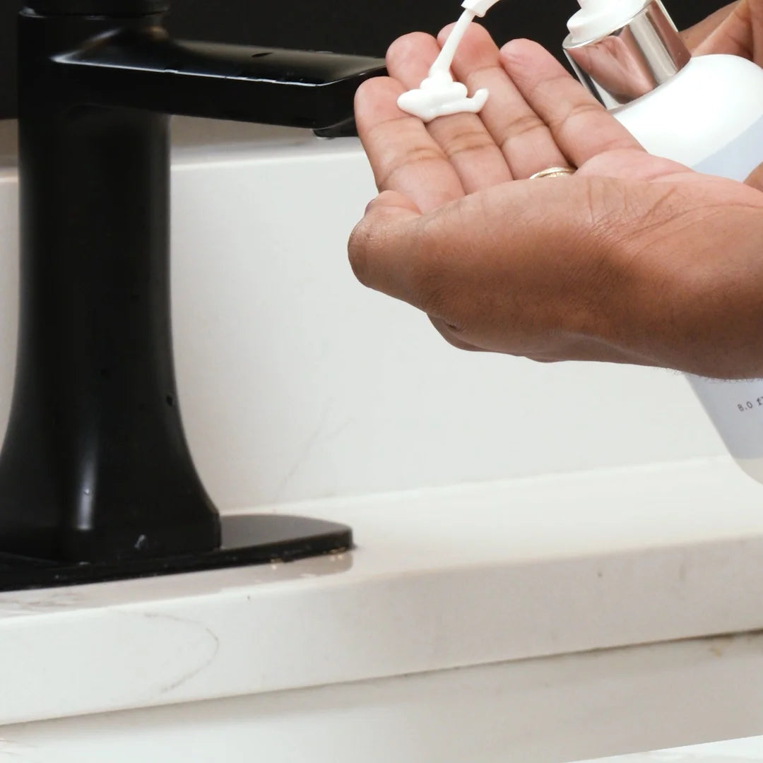 Hand holding a bottle of Glymed Plus Vitamin C Cleanser with a black and white background