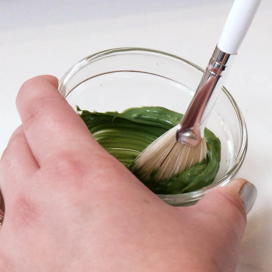 Hand holding a Glymed Plus White Fan Brush