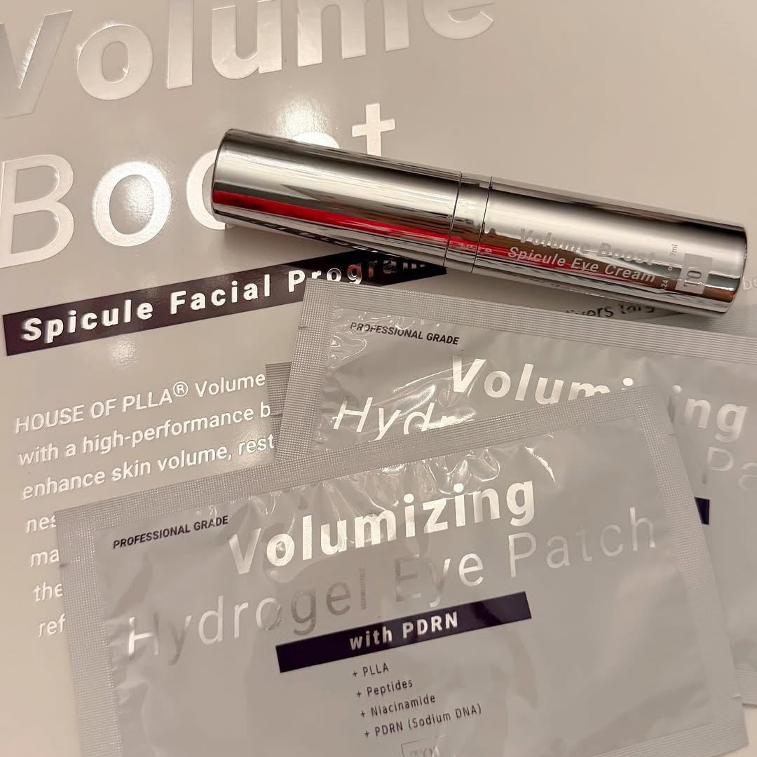 Spicule eye serums and Volumizing Hydrogel Eye Patch packaging from the House of PLLA Volume+ skincare set, featuring a silver and red pen-style serum tube resting on a white box.