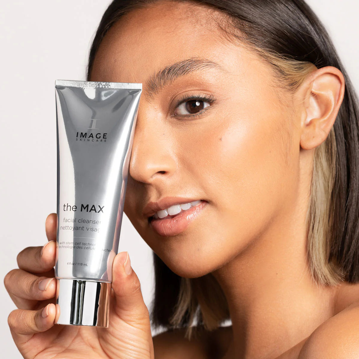 Woman holding a skincare product labeled 'the MAX' by Image Skincare.