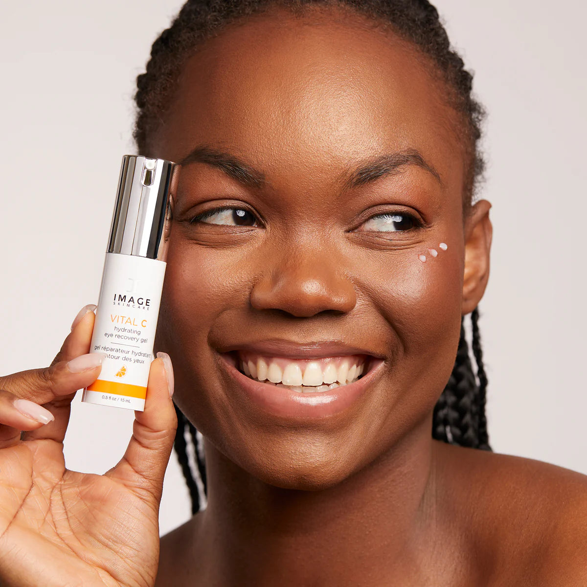 Woman holding a skincare product with a plain background