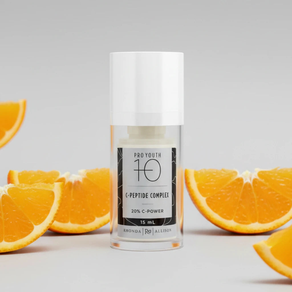 Skincare serum bottle labeled 'Pro Youth 10 C-Peptide Complex' with 'Rhonda Allison' branding on a light background and orange slices