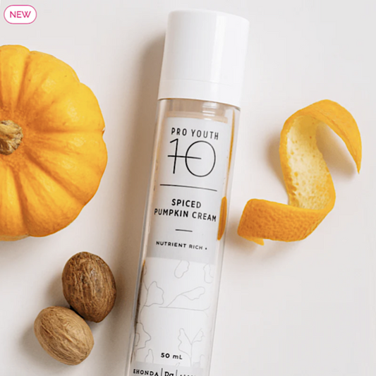 Spiced pumpkin cream bottle with a pumpkin, nutmeg, and orange peel on a white background