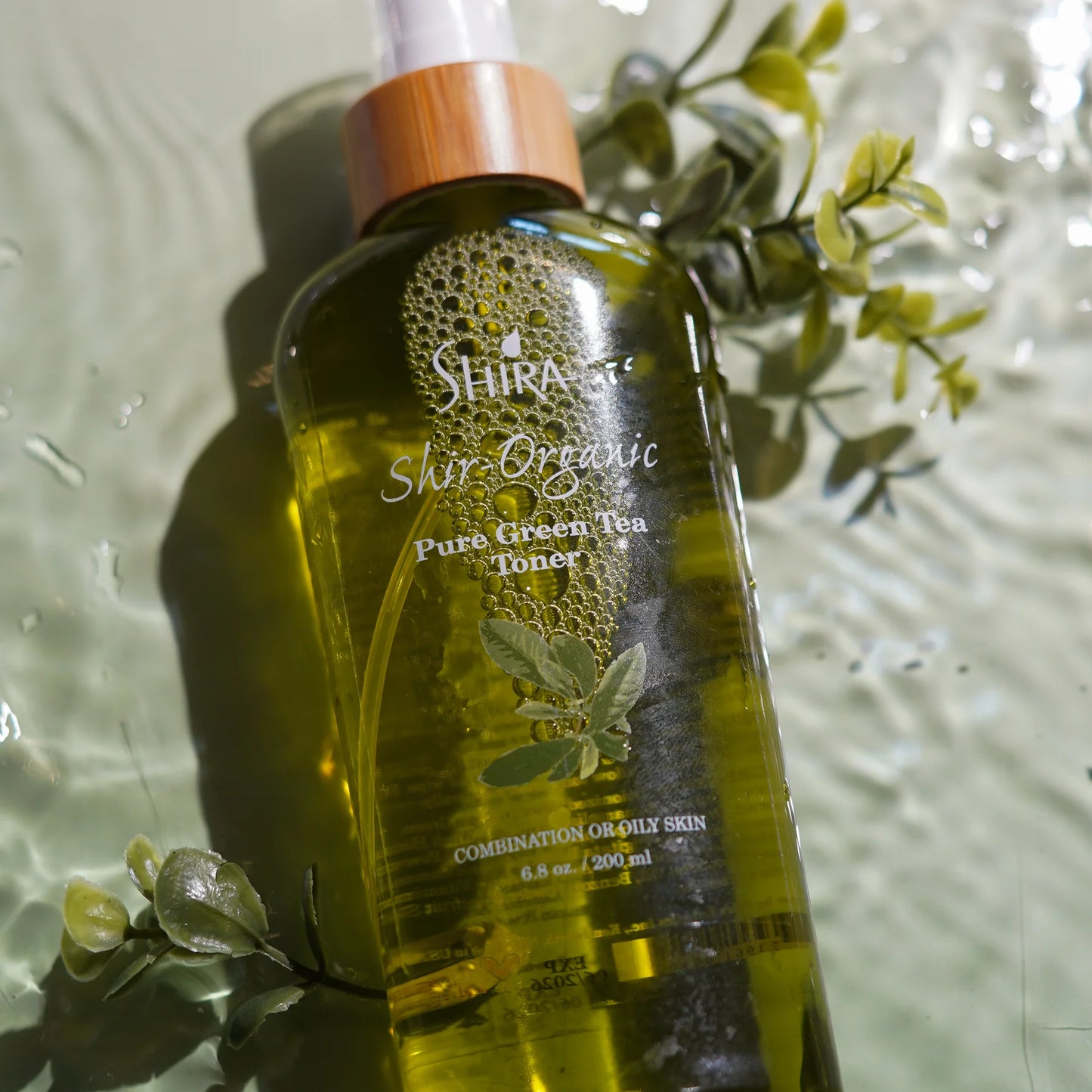 Shira Organic Pure Green Tea Toner bottle with green leaves on a reflective surface