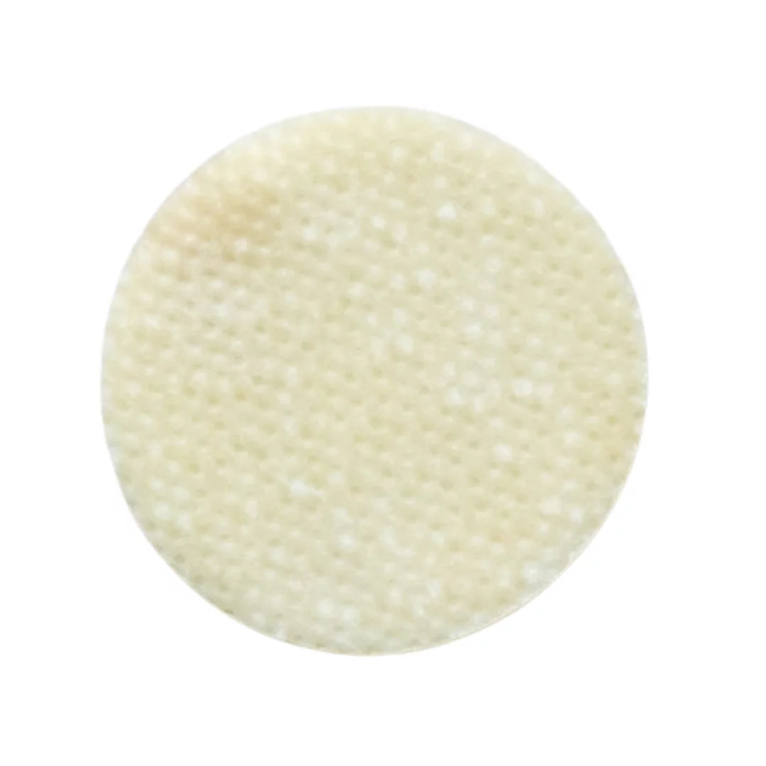 A round, textured cream-colored patch or Skin Script glycolic pad with a fine honeycomb-like surface, shown against a plain white background.