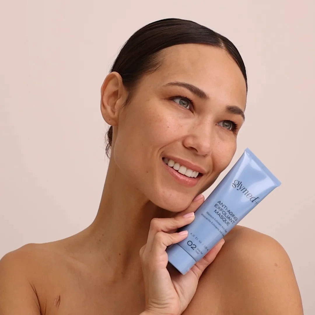 Woman holding a blue skincare product with a beige background