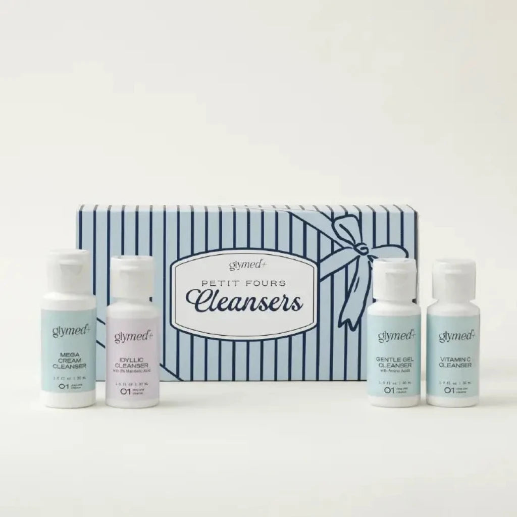 A gift set of five glymed Petit Fours Cleansers in small white bottles arranged in front of a blue and white striped gift box with a ribbon illustration.