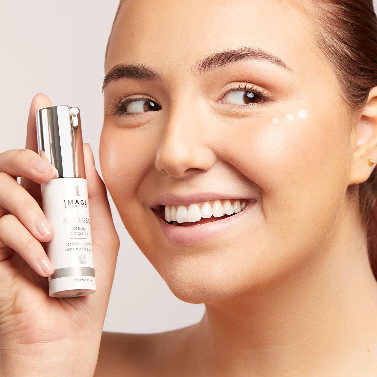 Woman holding a image skincare AGELESS_total_eye_lift_creme with a close-up of her face.
