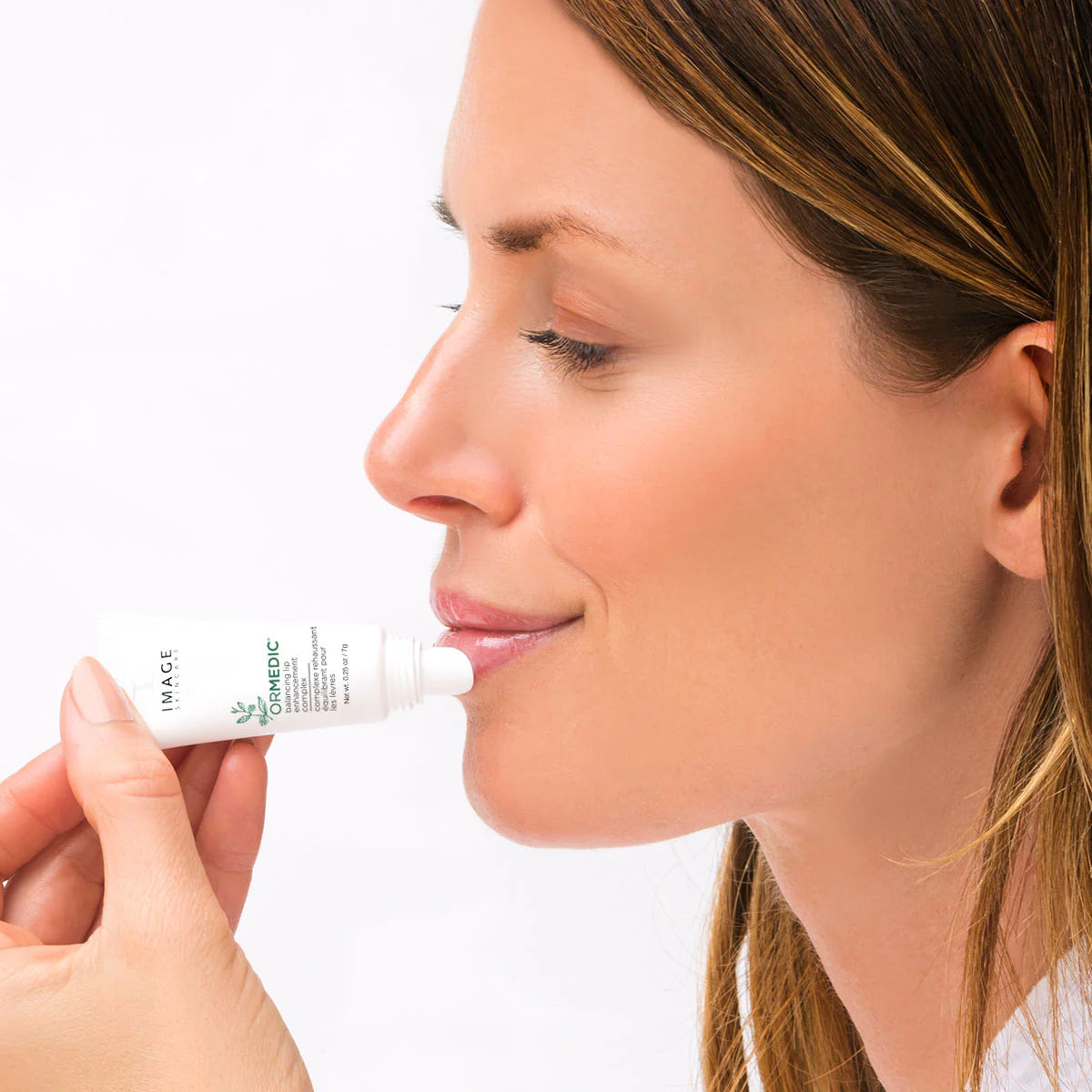 Woman applying a skincare product to her face with a white background