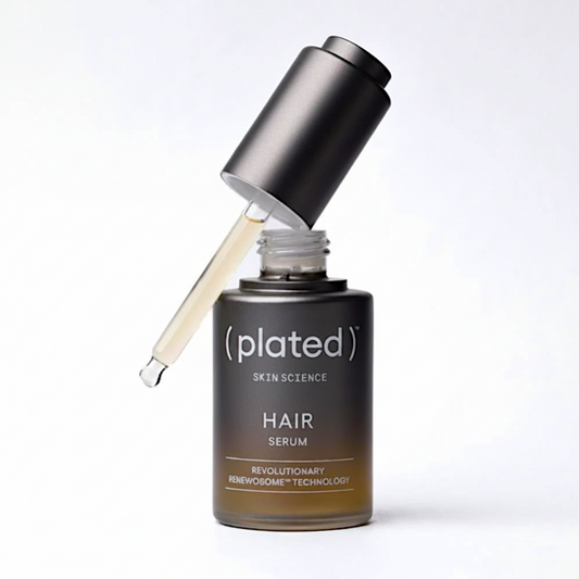 Plated hair serum bottle with applicator on a white background